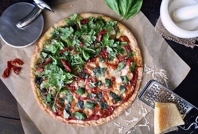 Healthy pizza variety with veggies, grated cheese and sundried tomatoes