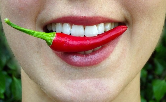 woman holding a chili pepper between her teeth